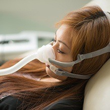 Woman sleeping with CPAP nose mask