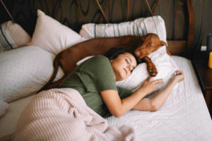 Woman sleeping in bed with dog