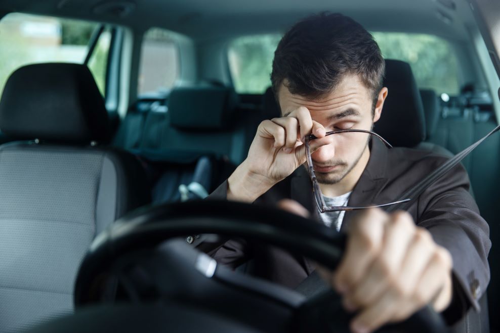 A tired man behind the steering wheel of a car